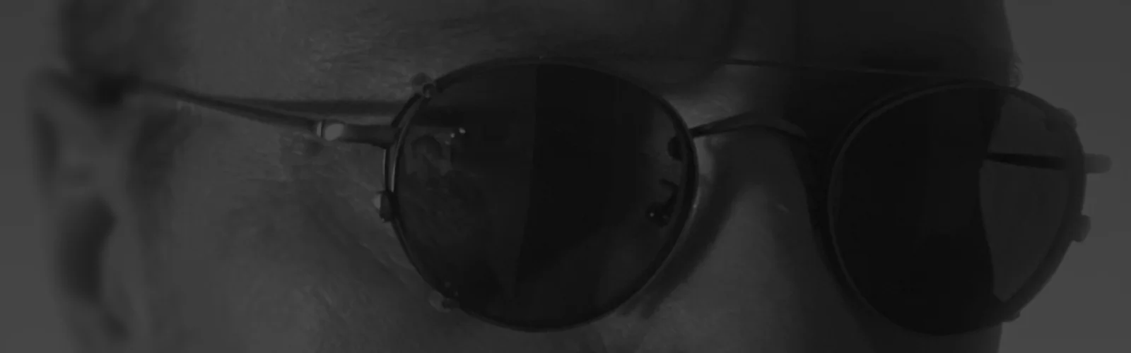 Das Gesicht einer Person, das teilweise durch eine dunkle Sonnenbrille verdeckt ist.
