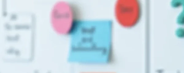 Unscharfes Bild von einer Wand, an der Ideen und Spickzettel für Marketing Maßnahmen.